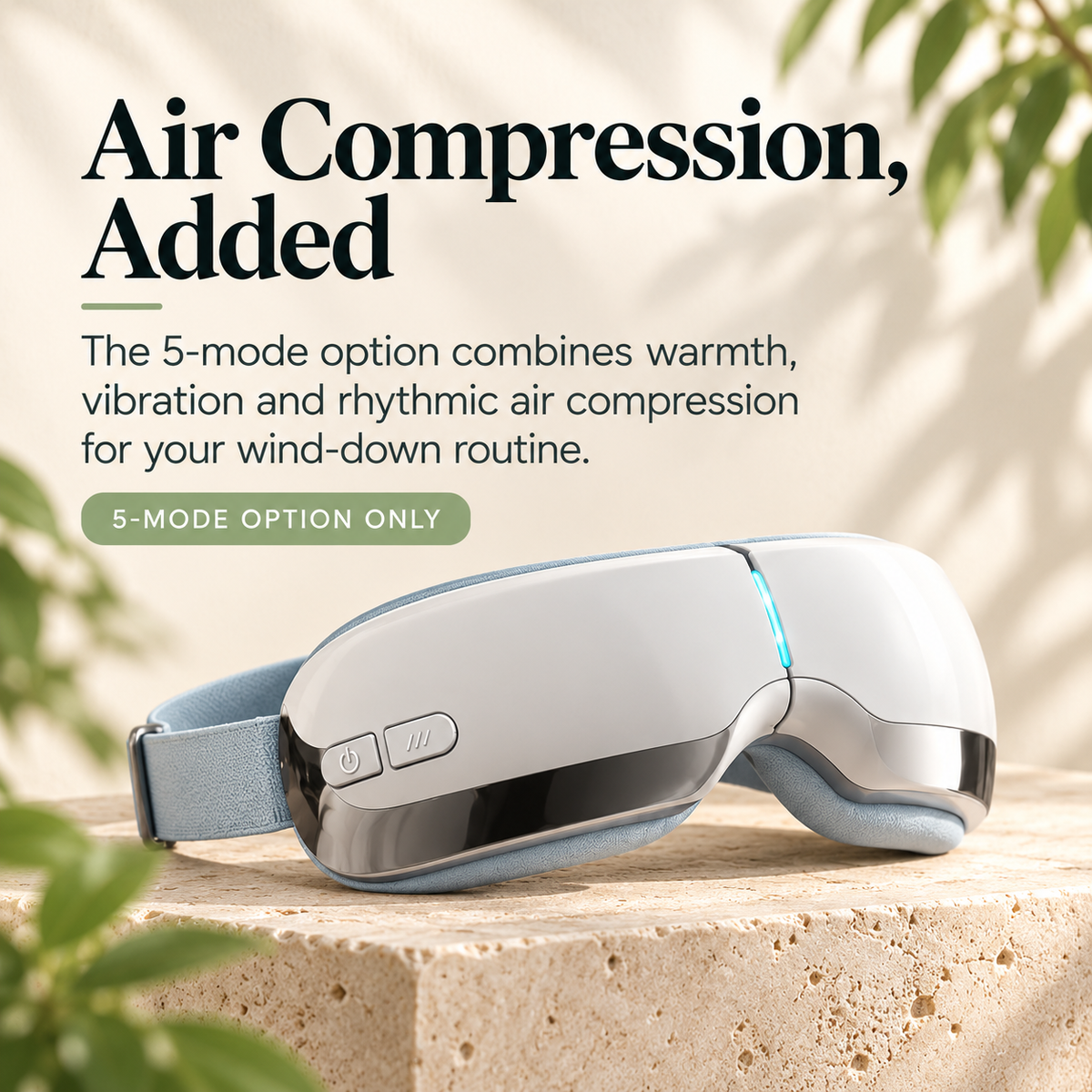 White ELM & ECHO 5-mode eye massager with a pale blue padded lining and adjustable strap on a stone display