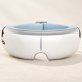 White heated eye massager with silver trim and a light blue adjustable strap
